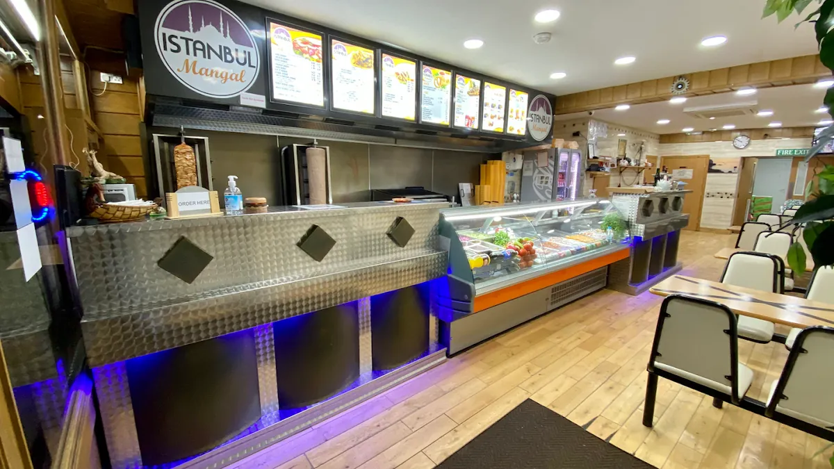 Inside Istanbul Mangal: the serving counter with doner spits and the illuminated menu boards