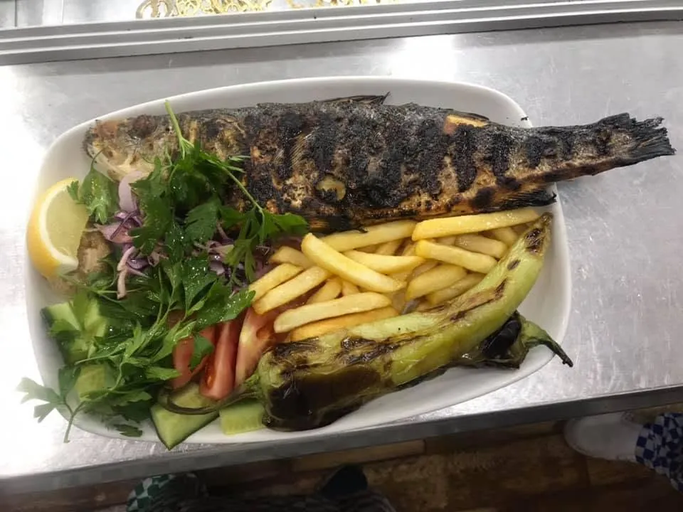 Whole charcoal-grilled sea bass with chips, grilled green pepper, salad and lemon